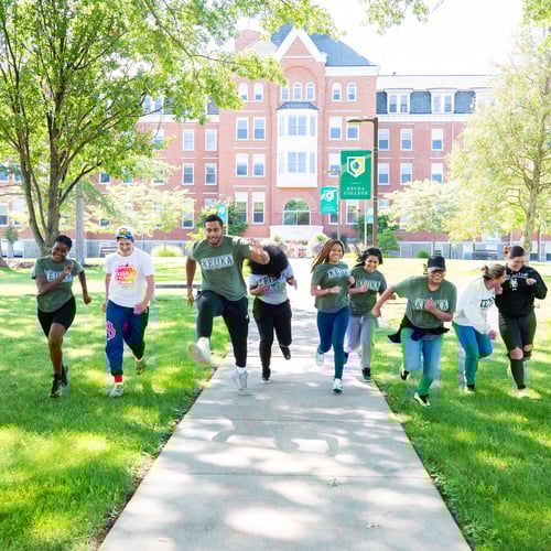 Students running toward the camera and away from Ball Hall